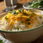 A bowl of white rice topped with melted shredded cheese and parsley.