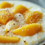 Mango sticky rice served with coconut milk and sesame seeds.