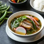 A serving of sinigang with tamarind broth, fresh vegetables, and rice.